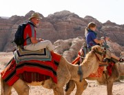 2 American guests of Engaging Cultures Travel riding camels on a Jordan tour