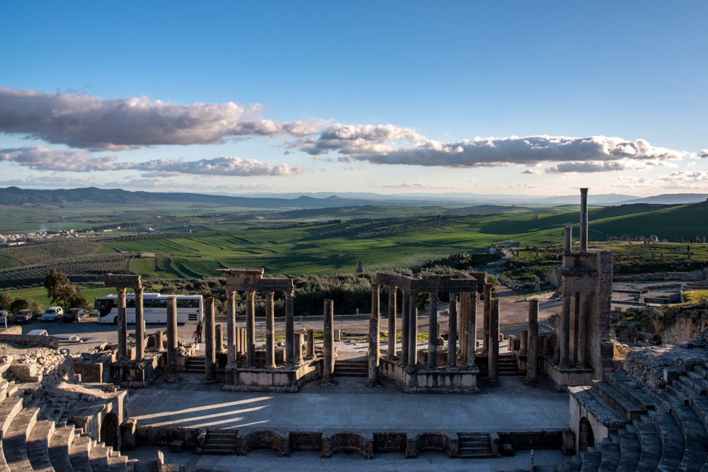 Roman amphitheatre in Dougga, Tunisia with view of lush, green hills in the background