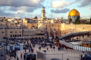 Scene at the Wailing Wall in Jerusalem with Dome of the Rock and Church steeple in the background